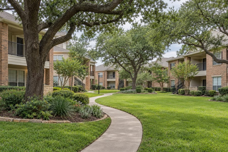 A garden-style Texas apartment community with mature trees and a landscaped courtyard